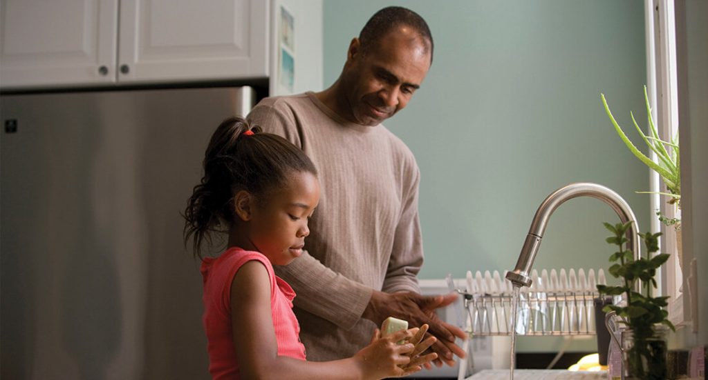 Pappa och dotter tvättar händerna tillsammans i köket
