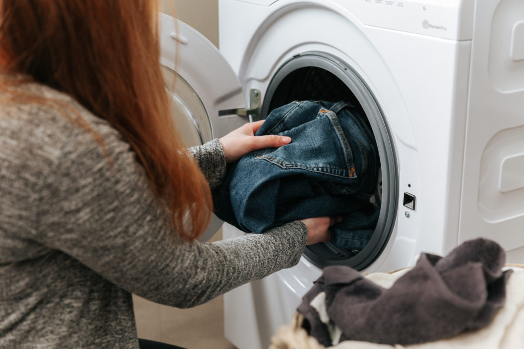 Kvinna stoppar in tvätt i tvättmaskinen.